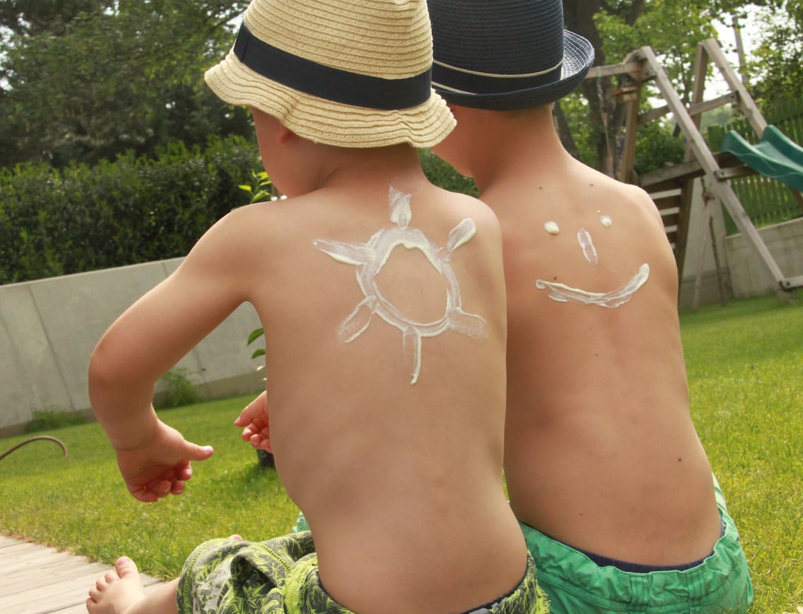 Zwei Buben mit Sonnencreme am Rücken für besseren Sonnenschutz